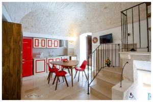 uma cozinha com armários vermelhos, uma mesa e cadeiras em Dimora dei Pentimi em Noci