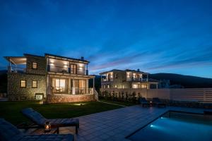 a villa with a swimming pool at night at White Villas in Karavomylos