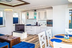 ブワディスワボボにあるFamily Homes - Apartament Blue Finの白いキャビネット、テーブルと椅子付きのキッチンが備わります。