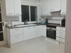 a white kitchen with white cabinets and a sink at Playa de Palma Beach House in Playa de Palma