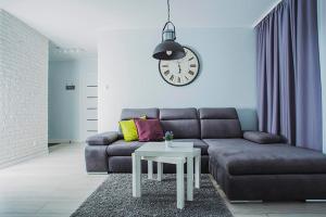 a living room with a couch and a clock on the wall at Holidays Home Apartamenty Chmielna in Gdańsk