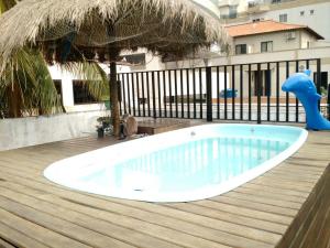 a swimming pool on a deck with an umbrella at Suítes Tropicana guesthouse in Cabo Frio