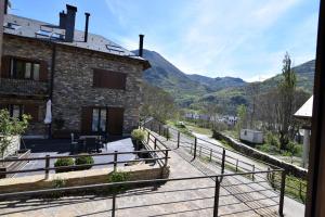 a stone house with a balcony and mountains in the background at Apartamentos L´Era de Baix in Barruera