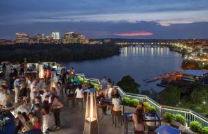 uma multidão de pessoas numa varanda com vista para um rio em The Watergate Hotel Georgetown em Washington