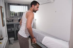 een man naast een bed in een kamer bij Monastiraki City Sleepbox- Unspoiled Athens Apartments in Athene