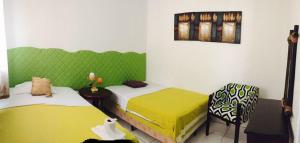 2 camas en una habitación con verde y blanco en Hostal Casa San Miguel en Masaya