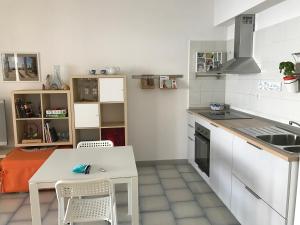 a white kitchen with a table and a table and chairs at Casa Paloma in Letojanni