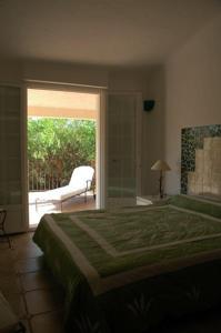 een slaapkamer met een bed en een glazen schuifdeur bij Residence La Beloutiere in Porto-Vecchio