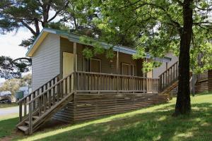 a small house with a large porch and a deck at Rainbow Pines Tourist Caravan Park in Adaminaby
