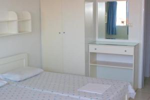 Cette chambre blanche comprend un lit et un miroir. dans l'établissement Galini Sea View Apartments Chalkidiki, à Nea Skioni