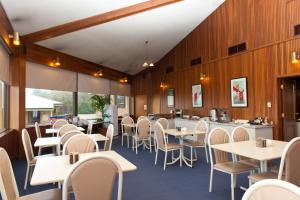 un comedor con mesas y sillas blancas en Admiral Motel Bunbury en Bunbury