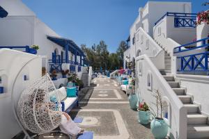 a woman sitting on a bench on a street with blue and white buildings at Samson΄s Village in Perissa