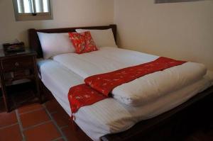 a bed with red and white sheets and pillows at Teapot House in Jinning