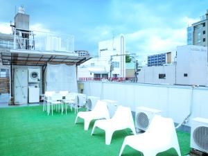 a balcony with white chairs and tables on a roof at Fukuoka Hana Hostel in Fukuoka