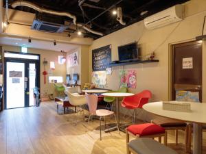 Fukuoka Hana Hostel في فوكوكا: مطعم به طاولات وكراسي وتلفزيون على الحائط