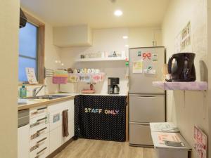 a small kitchen with a refrigerator and a sink at Fukuoka Hana Hostel in Fukuoka
