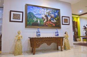 a painting on a wall with two figurines next to a table at The Cabin Tanjung Hotel Wonosobo in Wonosobo