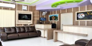 a waiting room with a leather couch and a television at Sara Regency in Palni