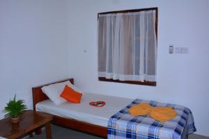 ein Schlafzimmer mit einem Bett mit orangefarbenen Kissen und einem Fenster in der Unterkunft Pleasant Park Holiday Inn in Trincomalee