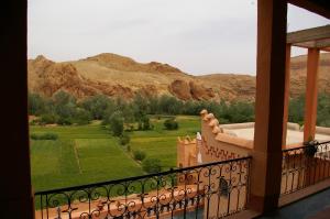 a balcony with a view of a field and mountains at Auberge Des Jardins du Dades in Boumalne