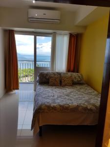 ein Schlafzimmer mit einem Bett und einem großen Fenster in der Unterkunft Taal Room in Tagaytay