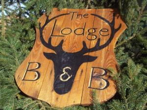 a wooden sign that says the lodge and bake in a tree at The Lodge B&B @ Cannock Chase in Cannock