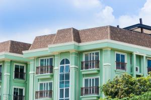 a green building with a brown roof at Dang Derm In The Park Khaosan in Bangkok