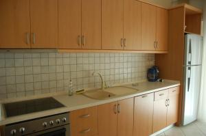 a kitchen with wooden cabinets and a sink and a refrigerator at Zefi's Apartment in Nea Peramos