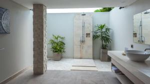 a bathroom with a sink and a shower with plants at Living Asia Resort and Spa in Senggigi