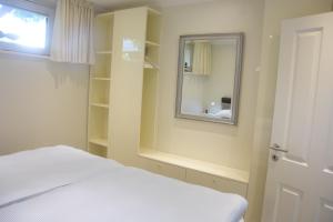 Schlafzimmer mit einem weißen Bett und einem Spiegel in der Unterkunft Ferienwohnung Smutje in Kiel