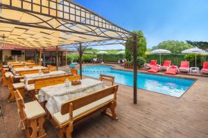 een patio met tafels en stoelen en een zwembad bij Akladi Family Hotel in Chernomorets