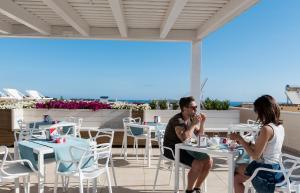 a man and a woman sitting at tables on a patio at Artemide Hotel in San Vito lo Capo