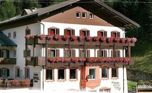 a large white building with flower boxes on it at Hotel Alpino Plan in Selva di Val Gardena