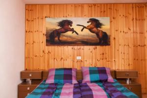 una camera con un letto e un dipinto di due cavalli di Apartmaji Mlekuž a Bovec