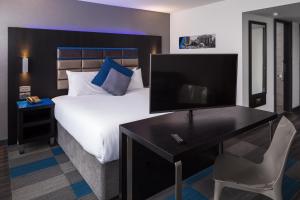 a hotel room with a large bed and a television at Roomzzz Nottingham City in Nottingham