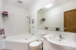 a bathroom with a tub and a sink and a toilet at Coranda Lodge in Armadale