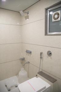 a bathroom with a toilet and a sink and a window at Hotel Orange International in Surat