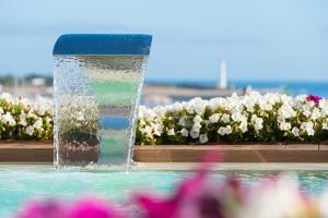 a fountain in a swimming pool with flowers at Artemide Hotel in San Vito lo Capo