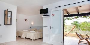 1 dormitorio con 1 cama y puerta corredera de cristal en Bungalows Sa Sargantana, en Playa de Migjorn