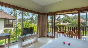 a living room with a television and a balcony at Living Asia Resort and Spa in Senggigi