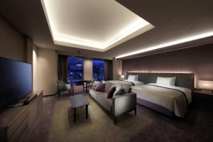 um quarto com uma cama, uma televisão e um sofá em Hotel Metropolitan Sendai East em Sendai