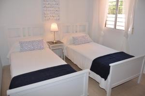 マール・デ・クリスタルにあるAlbatros Playa 2 - 9408の白いベッドルーム(ベッド2台、ランプ付)