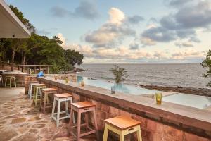 a bar with chairs and tables and a view of the ocean at Independence Hotel Resort & Spa in Sihanoukville