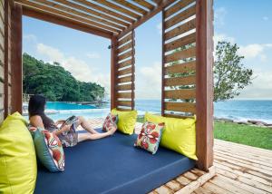 a woman sitting on a couch on a porch overlooking the ocean at Independence Hotel Resort & Spa in Sihanoukville
