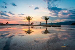 ein Spiegelbild des Sonnenuntergangs an einem Strand mit Palmen in der Unterkunft Guesthouse Storelli in Lopud Island