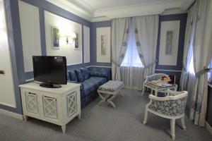 un soggiorno con divano blu e TV di Palazzo Alabardieri a Napoli