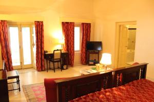 a bedroom with a bed and a living room with a television at Brijraj Bhawan Palace Hotel in Kota