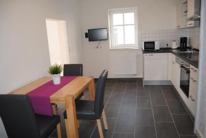 a kitchen with a wooden table and chairs and a kitchen with white cabinets at FEWO am Weinmarkt in Bad Windsheim