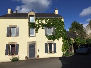 una casa amarilla con una puerta negra y hiedra en Vingt Vieux Bourg, en Rochefort-en-Terre