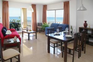 un soggiorno con tavolo, sedie e vista sull'oceano di Apartamentos Euromar Playa a Torrox Costa
